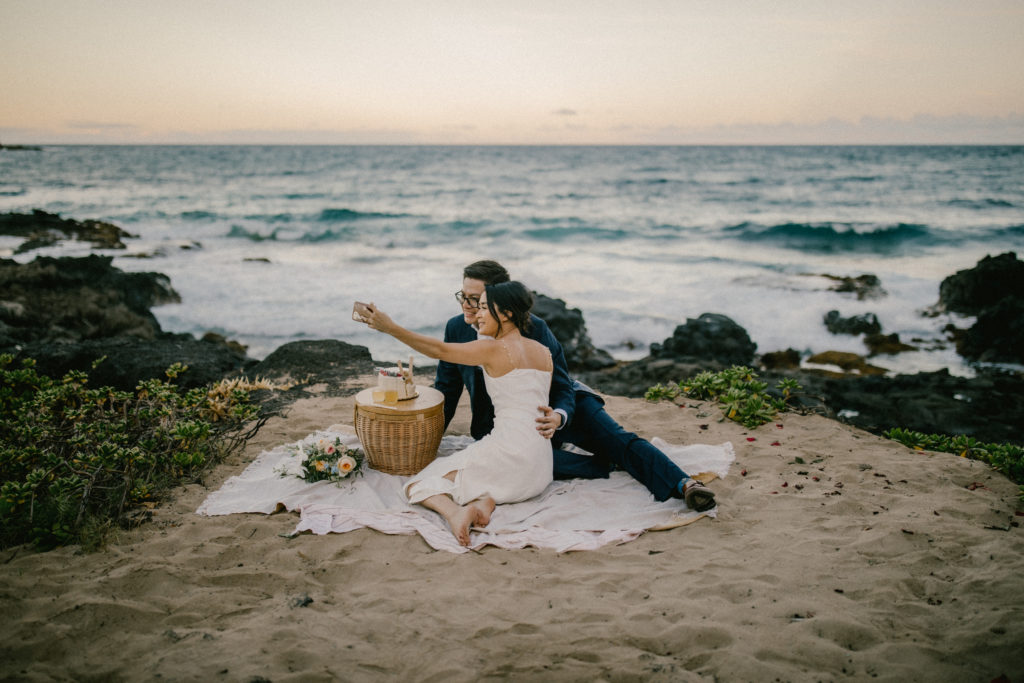 couple at their Hawaii Elopement sharing a picnic provided by the all-inclusive photo and video team