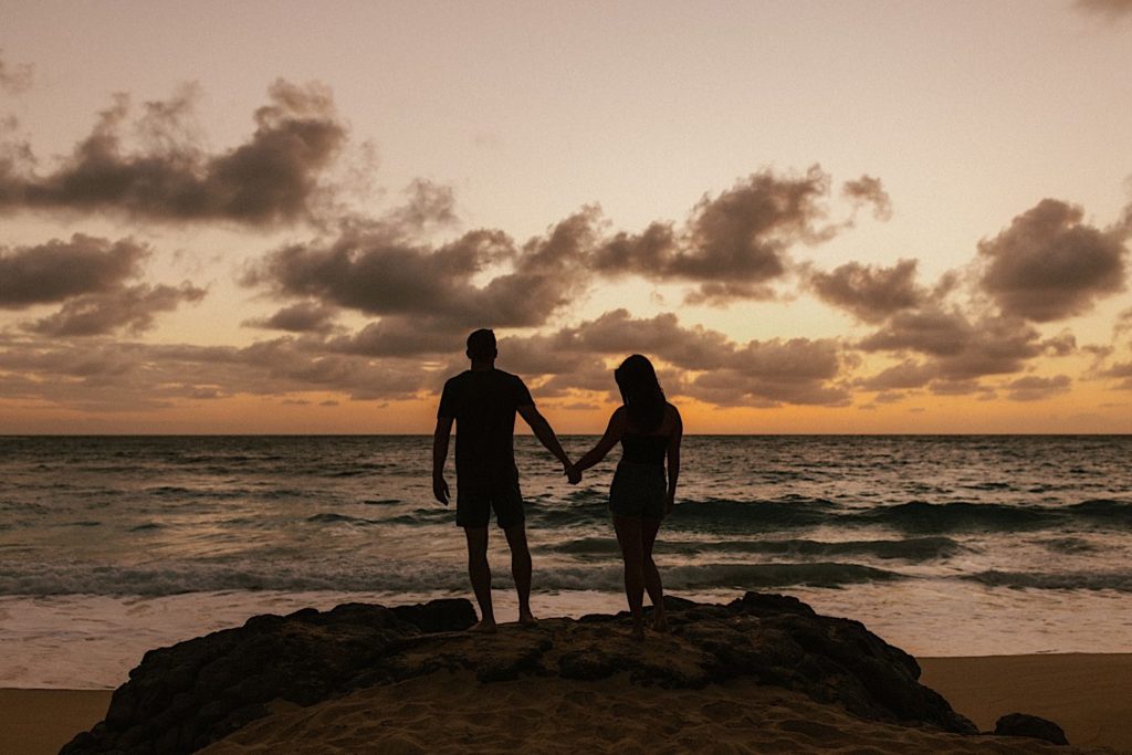 An image of an engaged couples' silhouette's standing on a Hawaii beach for their engagement session.
