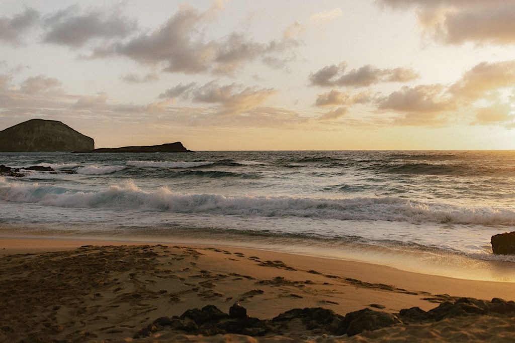 Waves splash in the distance on an Oahu beach at sunset.