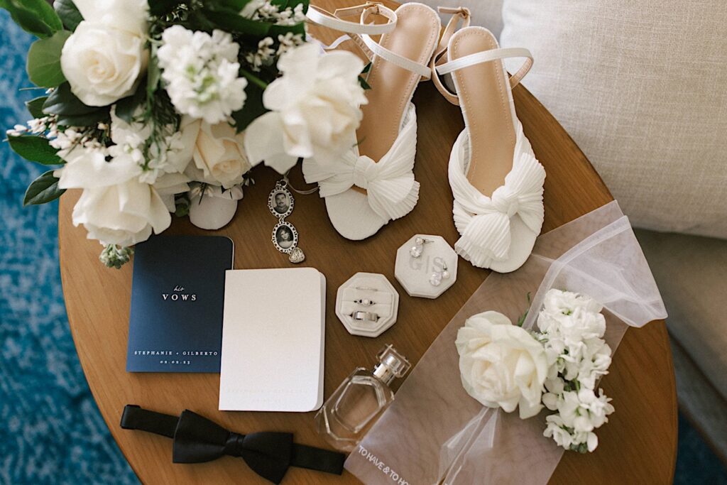 Photo of wedding details such as rings, shoes, vows and florals on a small table.