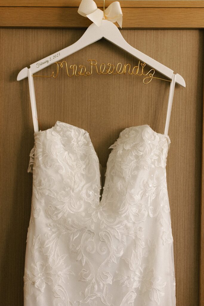 A wedding dress on a hanger with a wooden backdrop.