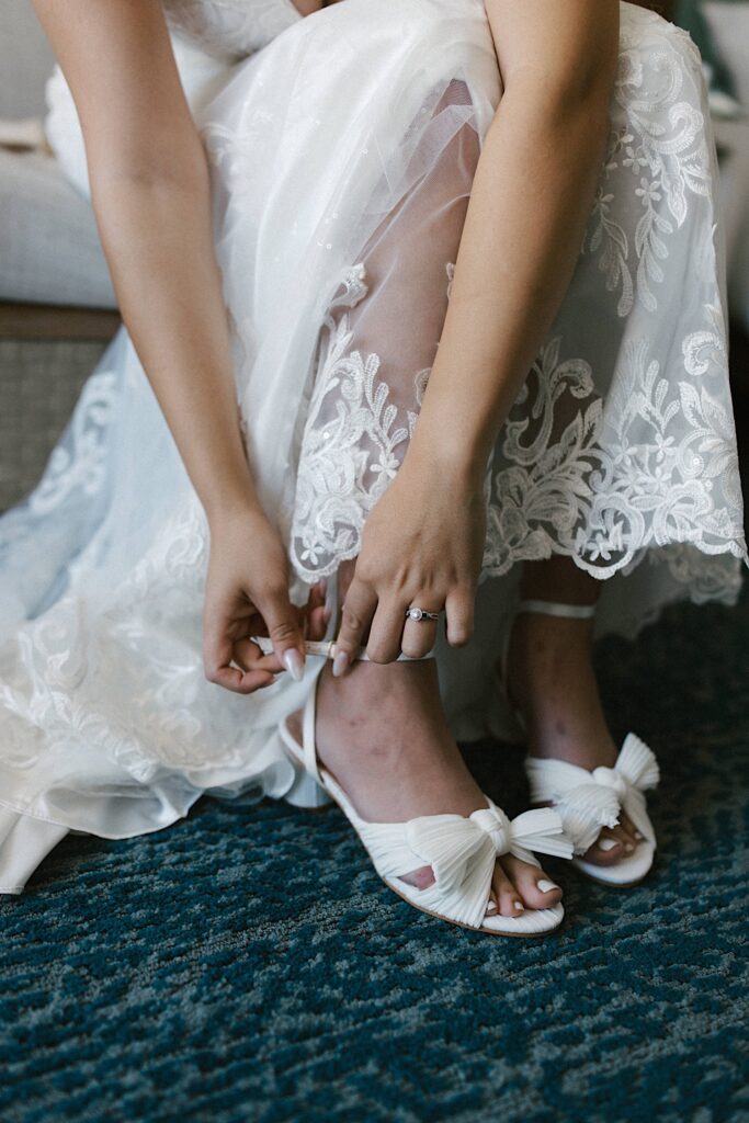 Close up of a bride sitting in her wedding dress and putting on her shoes before her wedding day