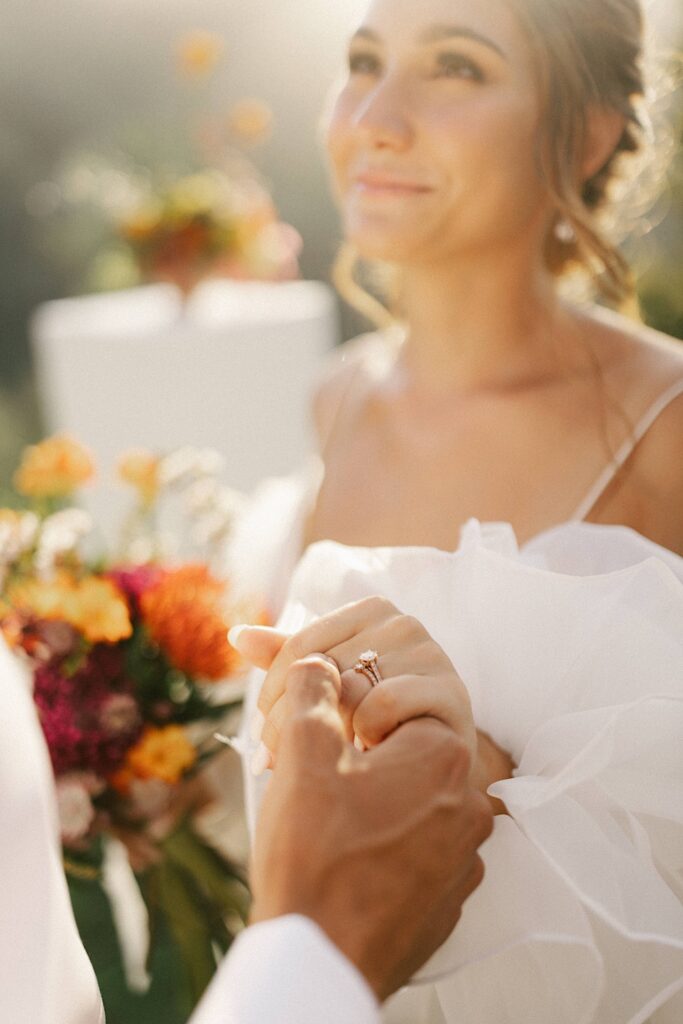 Closeup of a bride with her hand and wedding ring in focus.