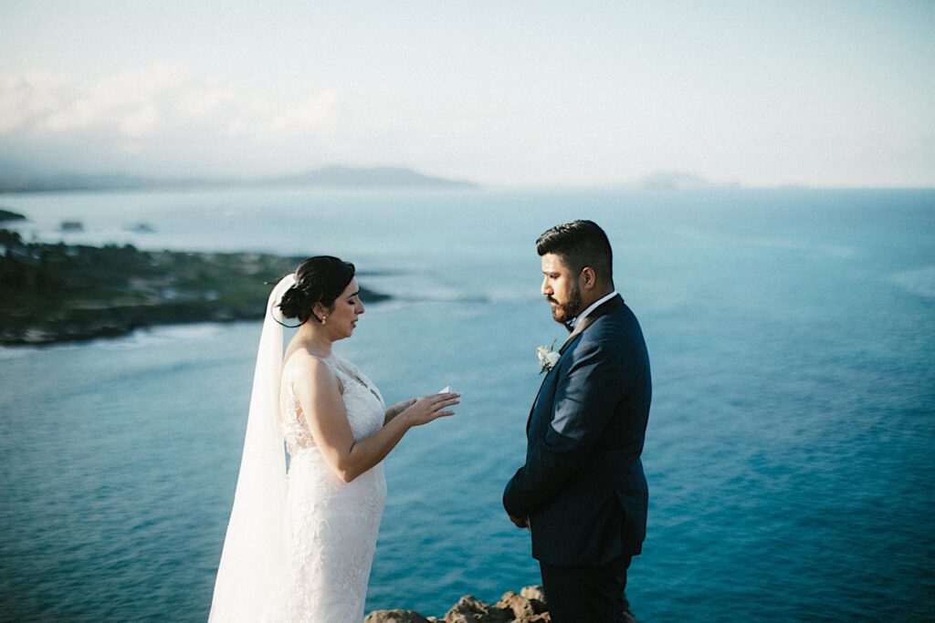 A bride tears up reading her vows to the groom during their elopement on a cliff overlooking Makapuu Beach.