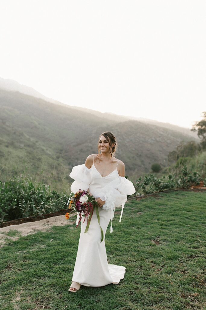 Portrait of a bride holding her bouquet with mountains behind her.
