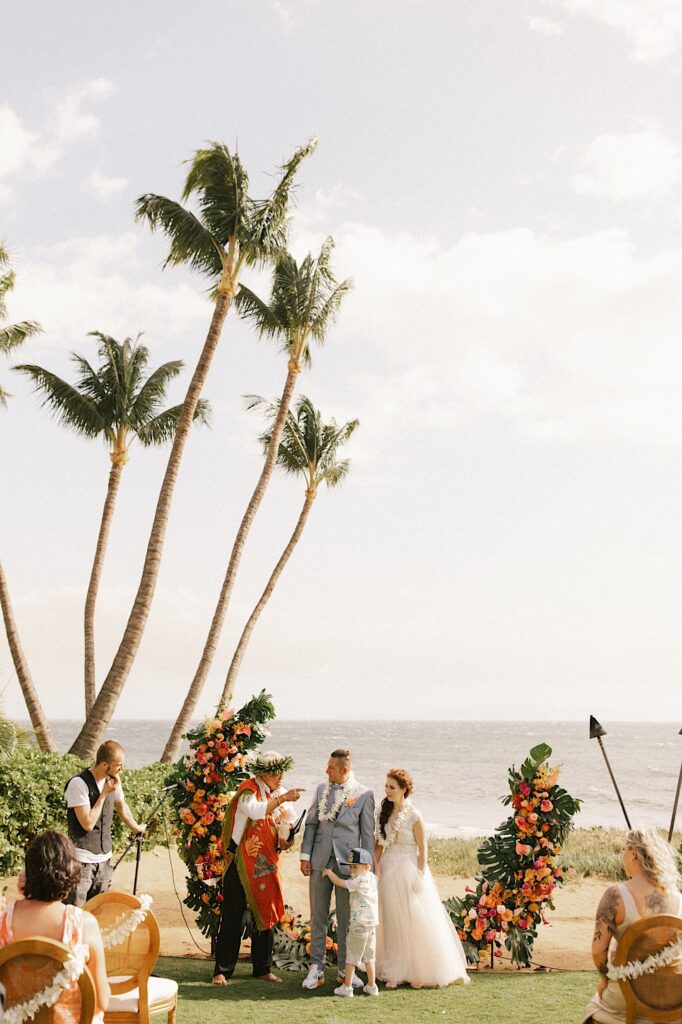 A wedding ceremony taking place on one of the beaches of Maui with the ocean in the background.