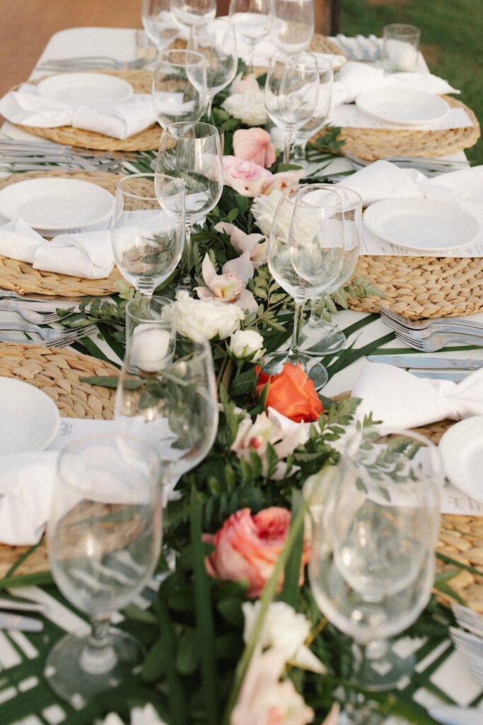 Detail photo of a table set up for a wedding reception with florals, glasses and plates.