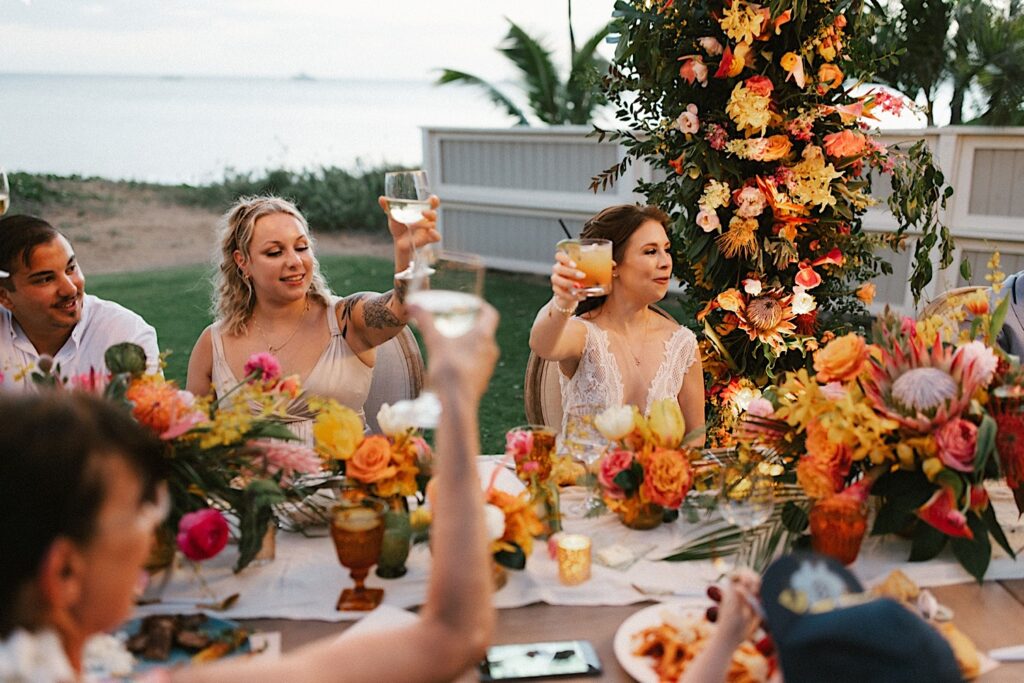 A bride and guests raise their glasses for a toast during a speech