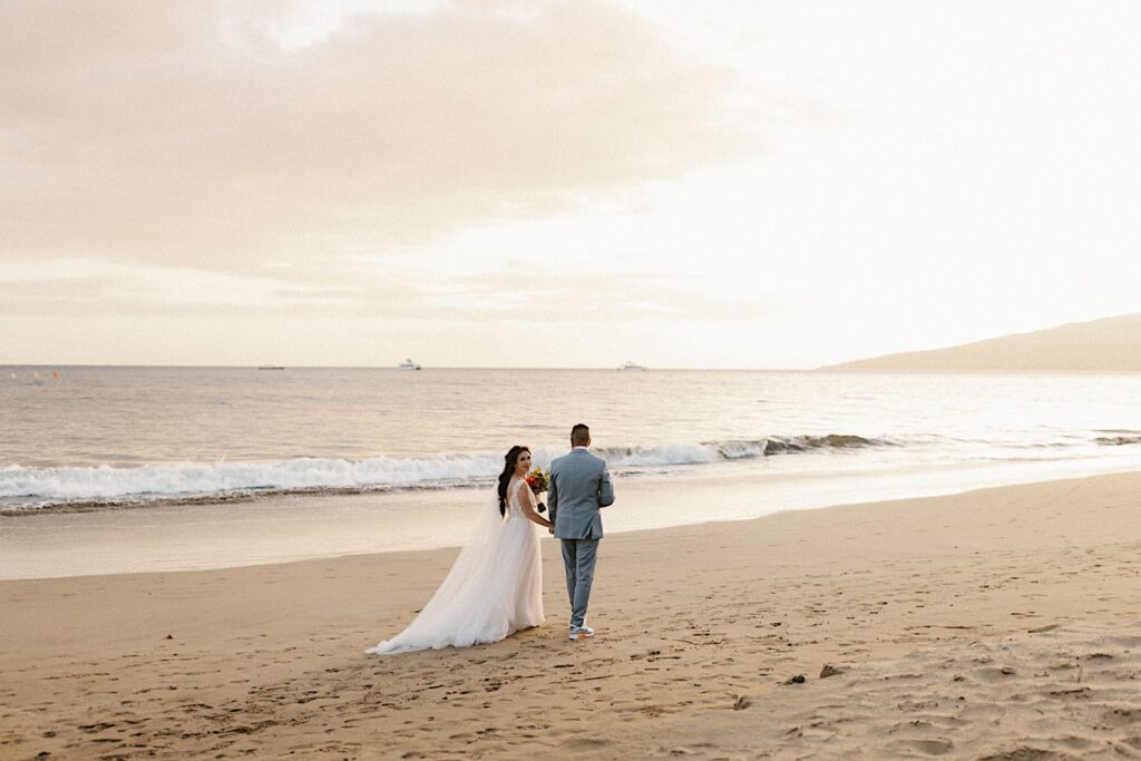 A newlywed couple walking along the beach of Maui after their wedding ceremony at Sugar Beach Events.