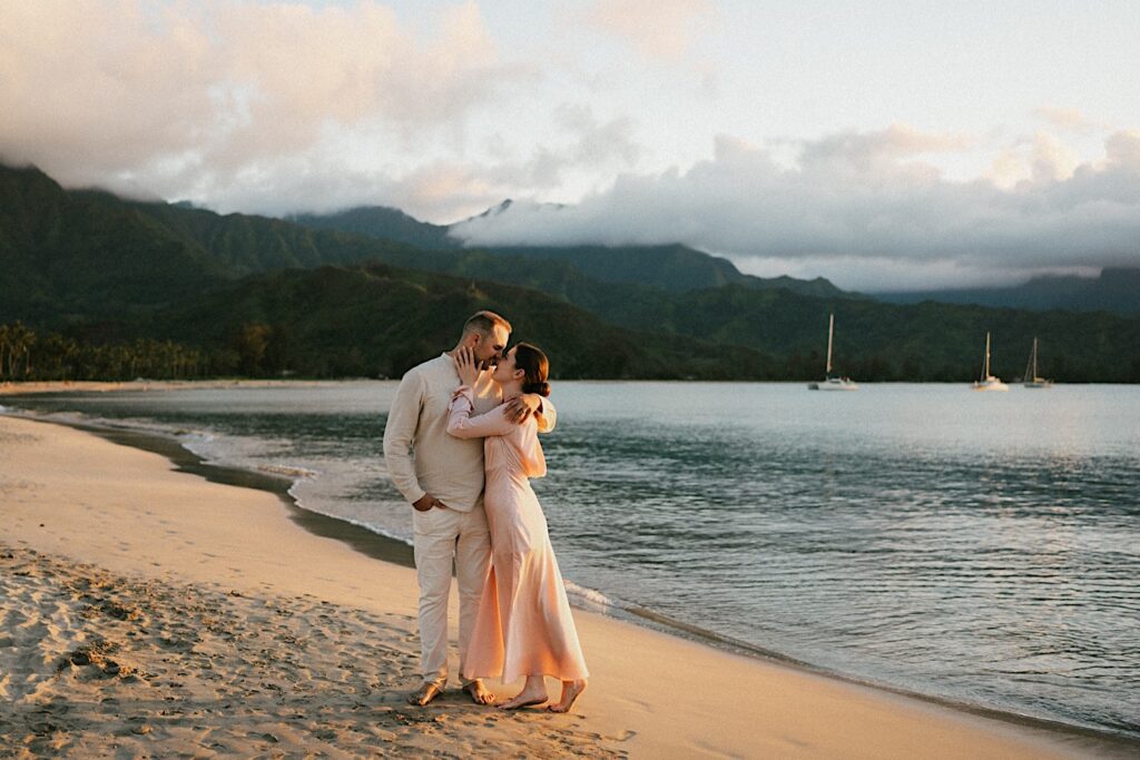 A couple on the beach embrace and are about to kiss during their engagement session in Hawaii
