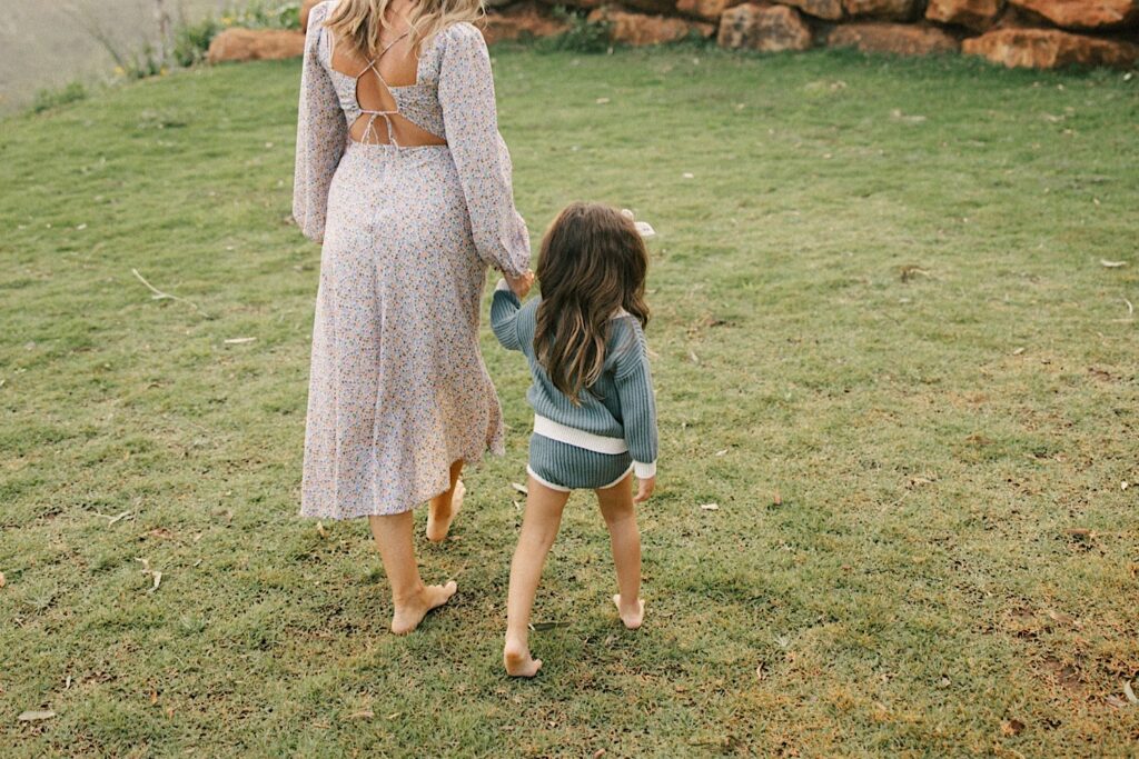 A mother walks away from the camera while holding her youngest daughter's hand during a family session on Oahu