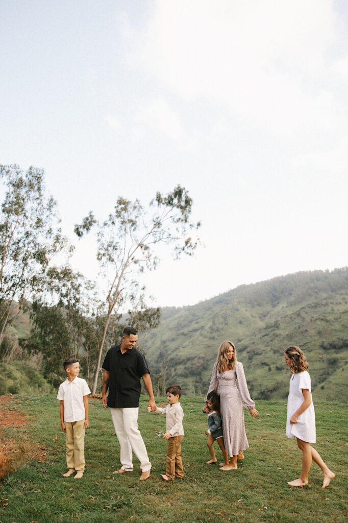 A family stand together and hold hands in a mountain range on Oahu