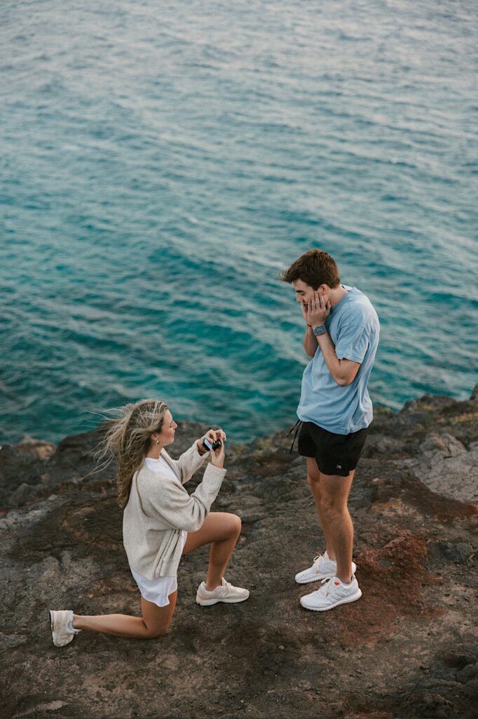 After being proposed to a woman flips the roles and proposes to her now fiancé who acts shocked, they're standing atop Makapuu Lookout which looks out over the ocean