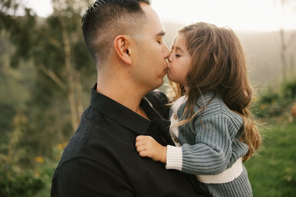 A father kisses his youngest daughter during their family session on Oahu