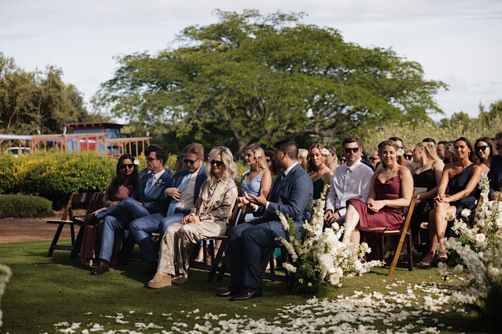 Wedding guests sit and talk with one another while waiting for the ceremony to start at Kukui'ula on Kauai