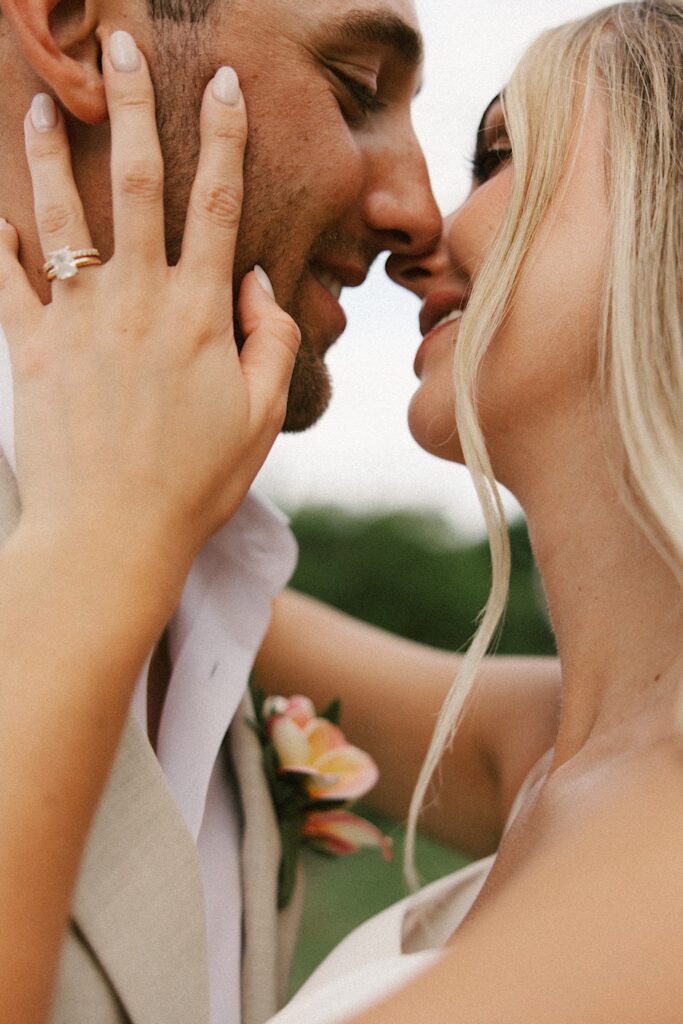 Close up photo of a bride and groom smiling at one another as they are about to kiss