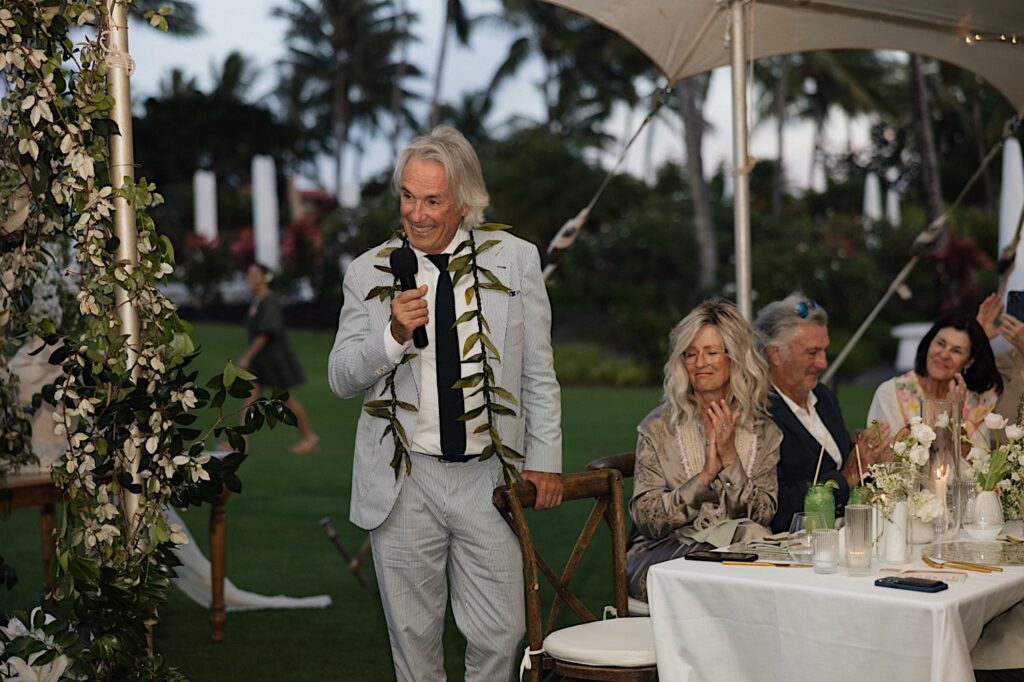 A father stands while giving a speech during a wedding reception underneath a tent at Kukui'ula on Kauai