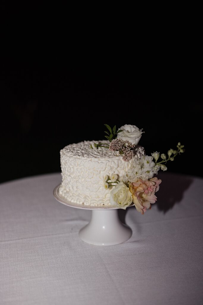 Detail photo of a wedding cake sitting on a cake tray on a table at night
