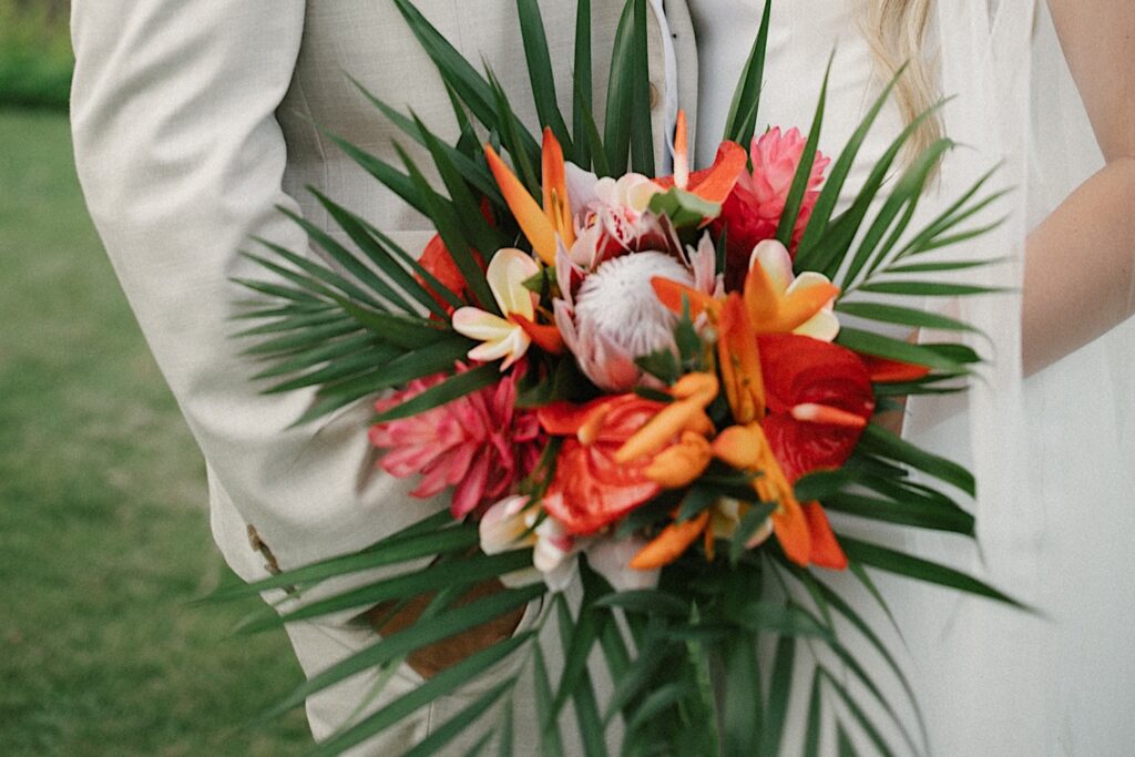 Close up photo of a bouquet being held in front of a bride and groom