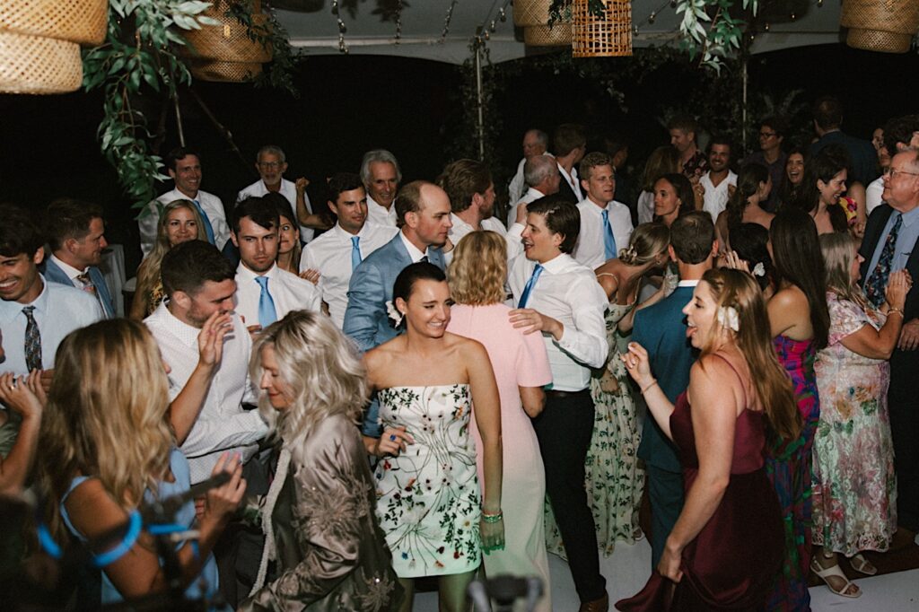 A bride and groom dance with the guests of their wedding reception around them at their wedding venue Kukui'ula on Kauai