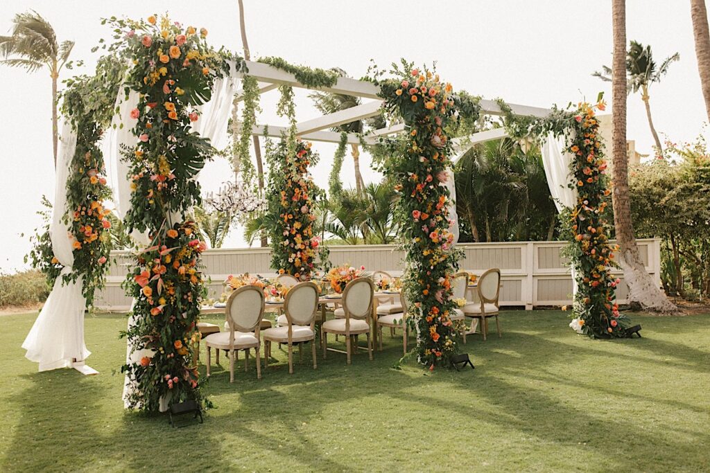An outdoor reception space of an intimate wedding venue on Maui called Gather in Maui, the space is decorated in orange and pink flowers
