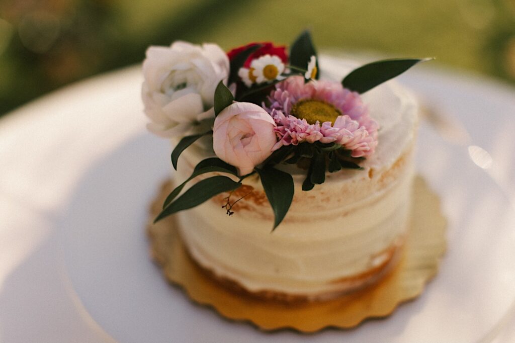 Detail photo of a wedding cake with pink and white flowers on it sitting on a table