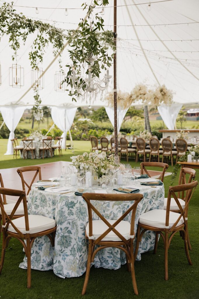 A table set up and decorated for a wedding reception underneath a tent