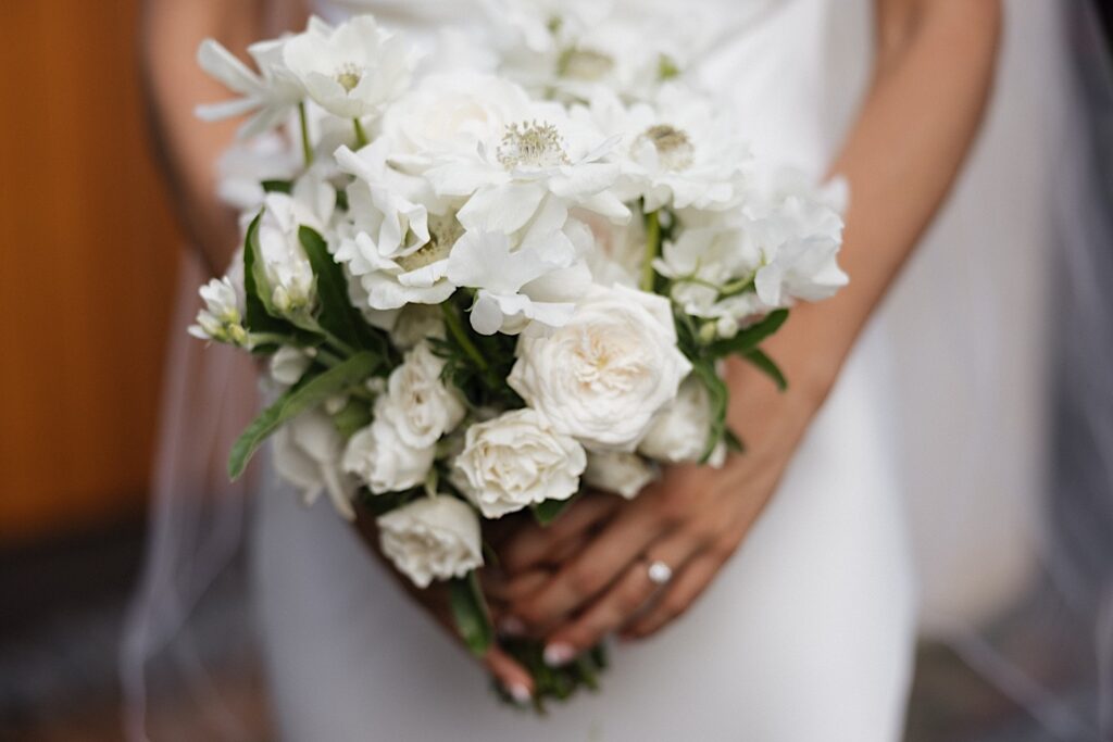 Close up photo of a white flower bouquet being held by a bride