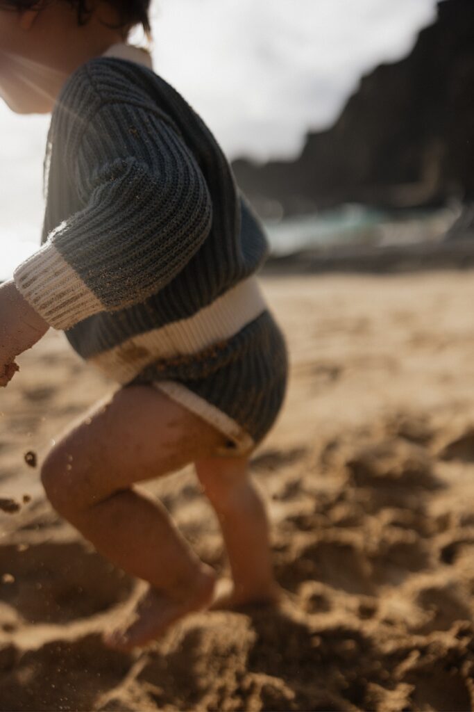 Close up photo of a young child running in the sand on a beach