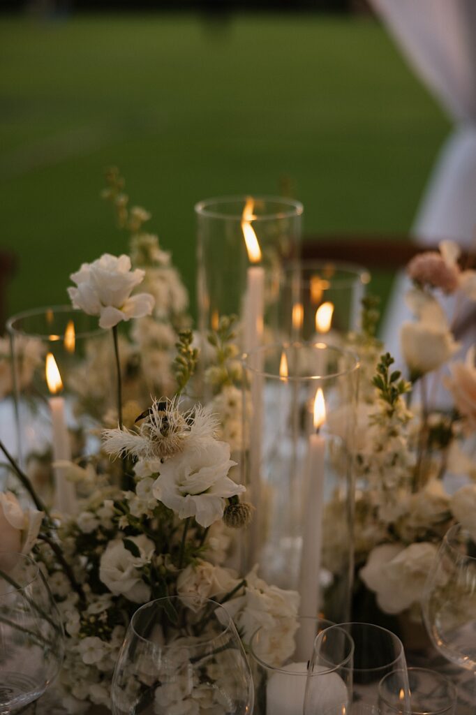 White flowers and candles sit next to one another on a table