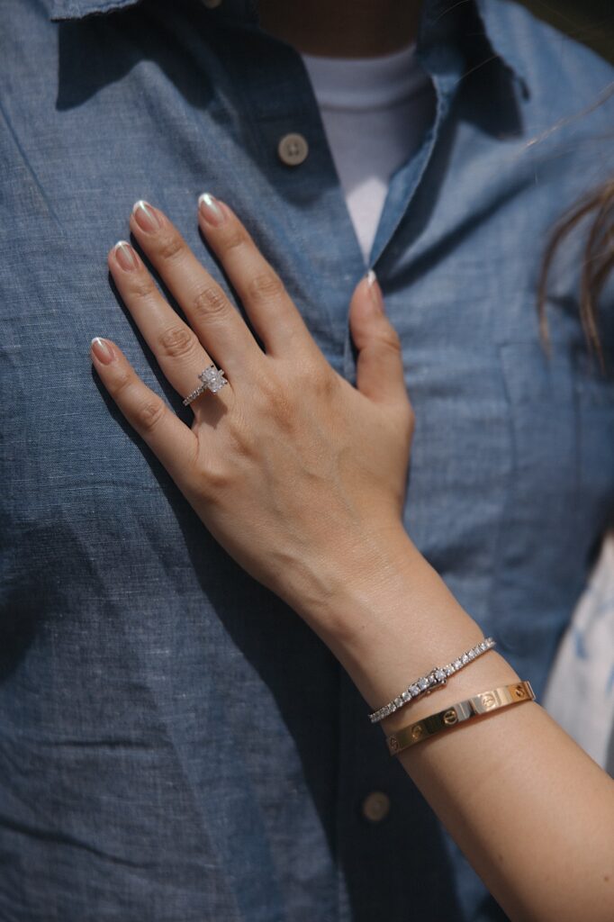 A woman's hand with an engagement ring on it rests on a man's chest