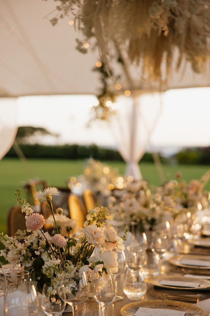 A table underneath a tent is decorated for a wedding reception as the sun sets