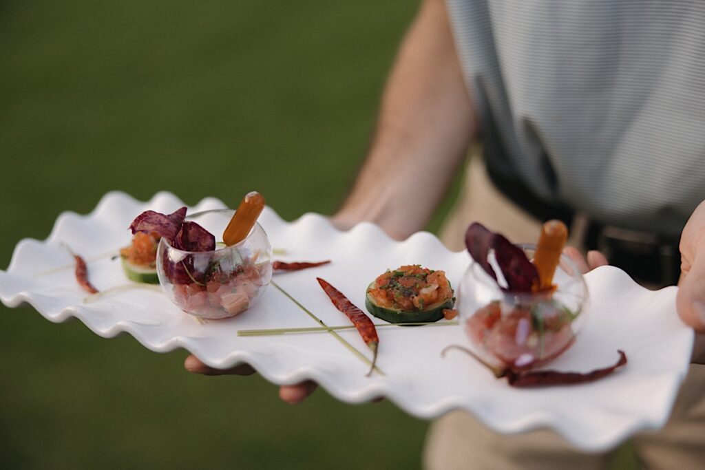 An appetizer tray is held out in front of the camera by a staff member of the wedding venue Kukui'ula