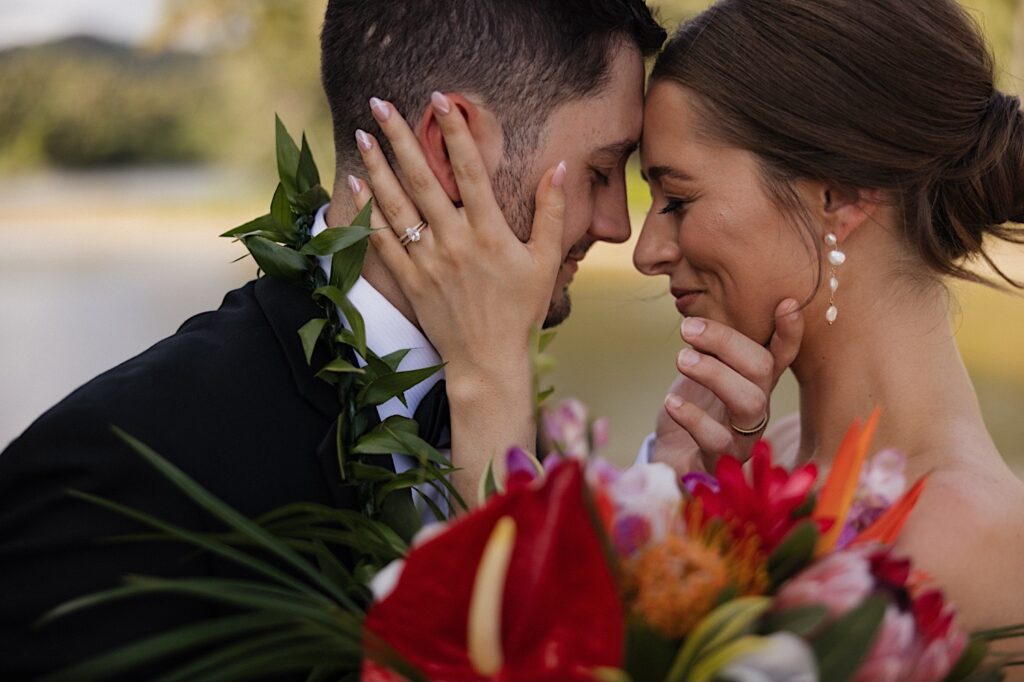 Close up photo of a bride and groom smiling at one another with their eyes closed on their elopement day in Hawaii