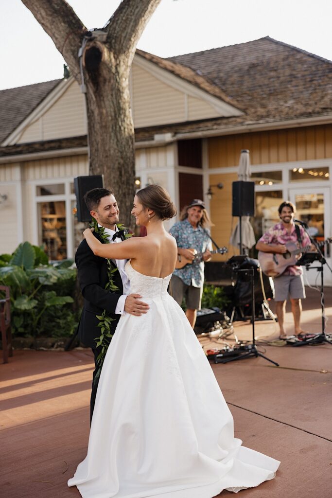 A bride and groom share their first dance together during their wedding day as live musicians play behind them