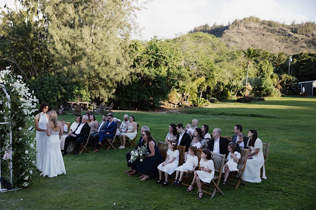 An LGBTQ wedding ceremony between two brides takes place as guests watch, the wedding is at Loulu Palm on Oahu's outdoor space