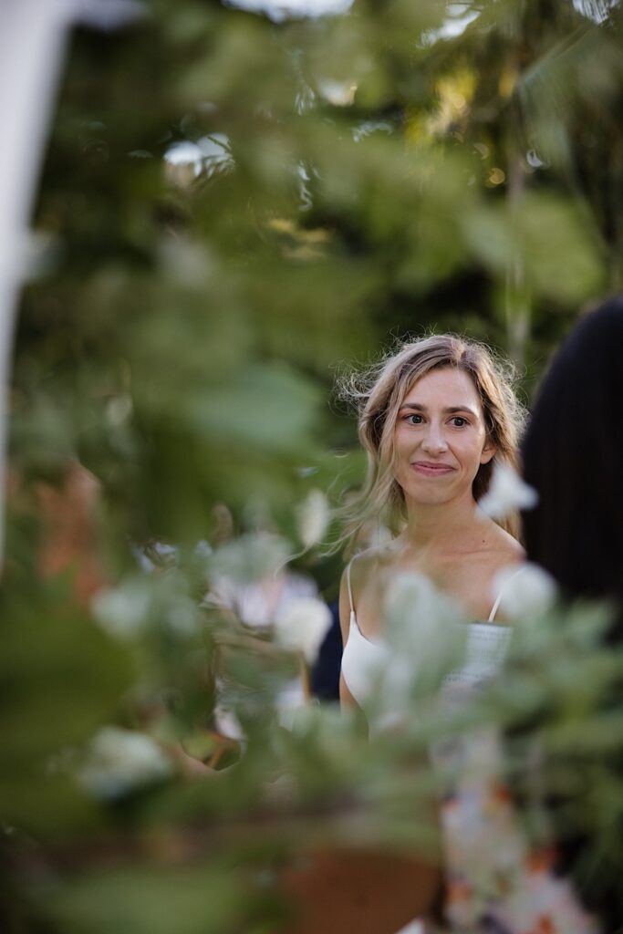 A bride smiles towards the camera during her outdoor wedding ceremony
