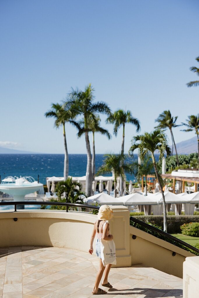 A child looks out towards the ocean while walking down the stairs of the Four Seasons Resort on Maui