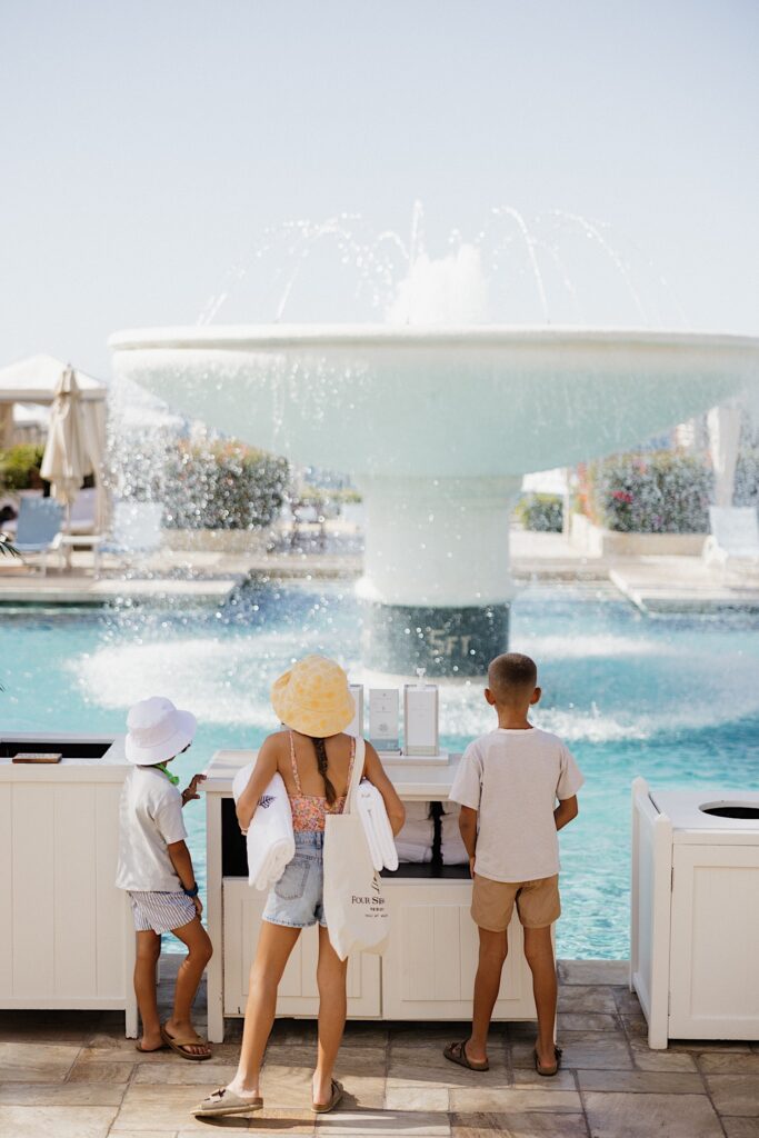 3 Children look at a large fountain that is in the middle of a pool at the Four Seasons Resort on Maui