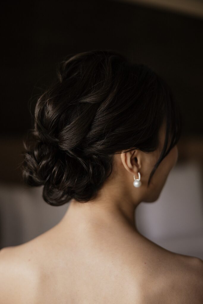 A bride faces away from the camera and looks to the right showing her earring and her hair on her wedding day