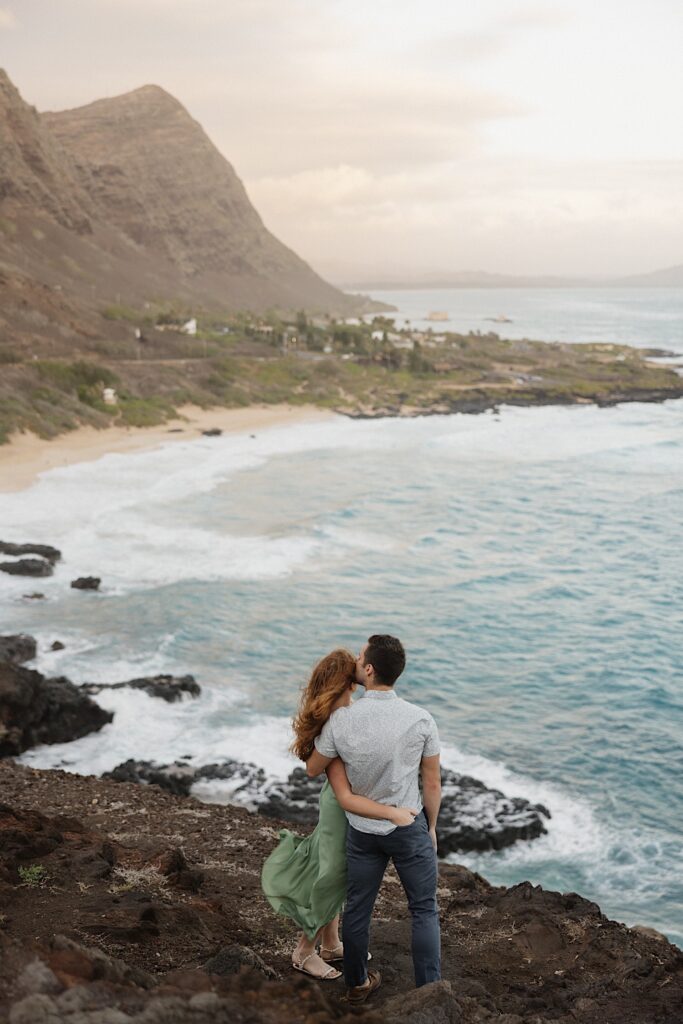 A couple embrace while standing side by side atop Makapuu Lookout on Oahu