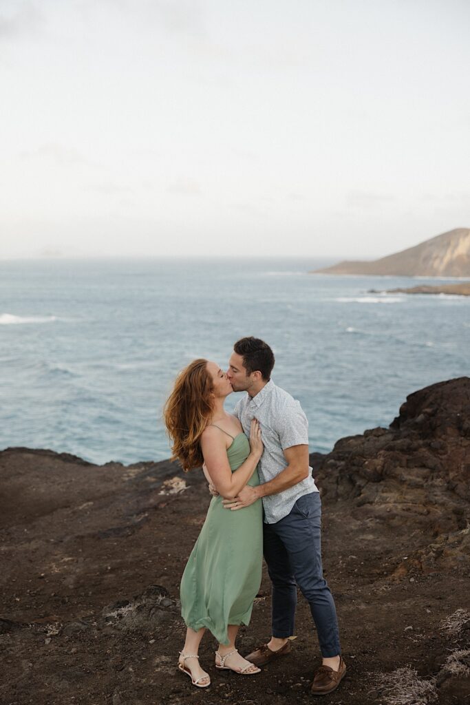 A couple kiss one another while standing on Makapuu Lookout on Oahu