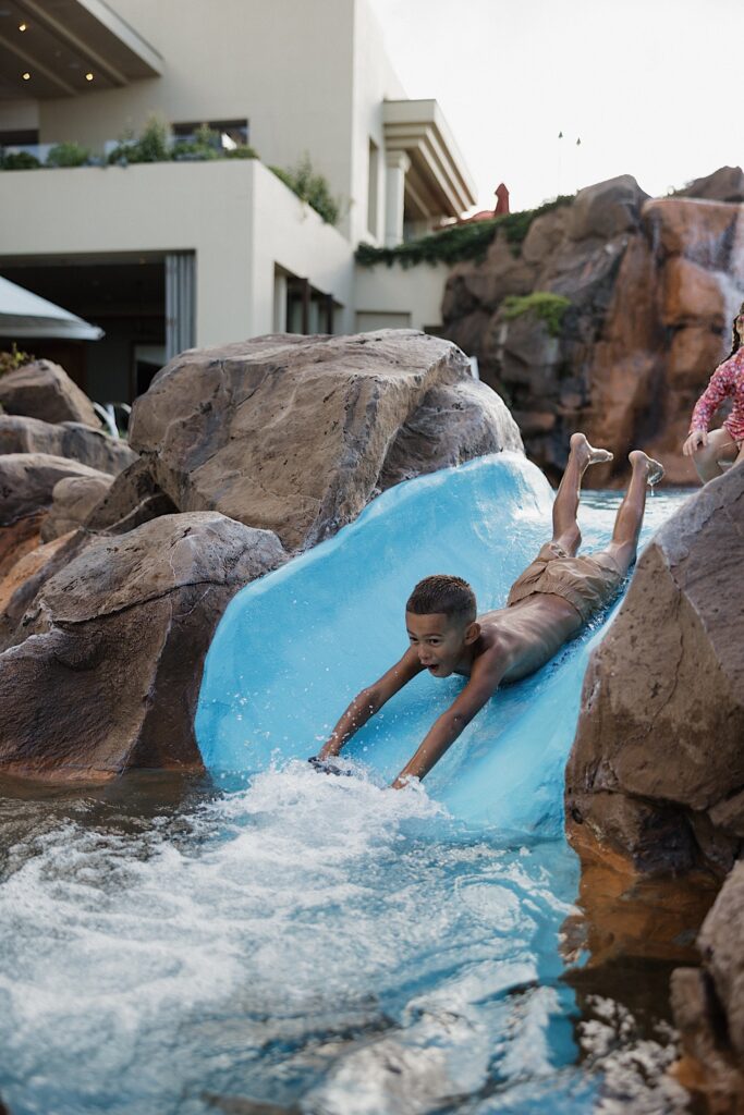 A young child slides down a a water slide on his belly at the Four Seasons Resort on Maui
