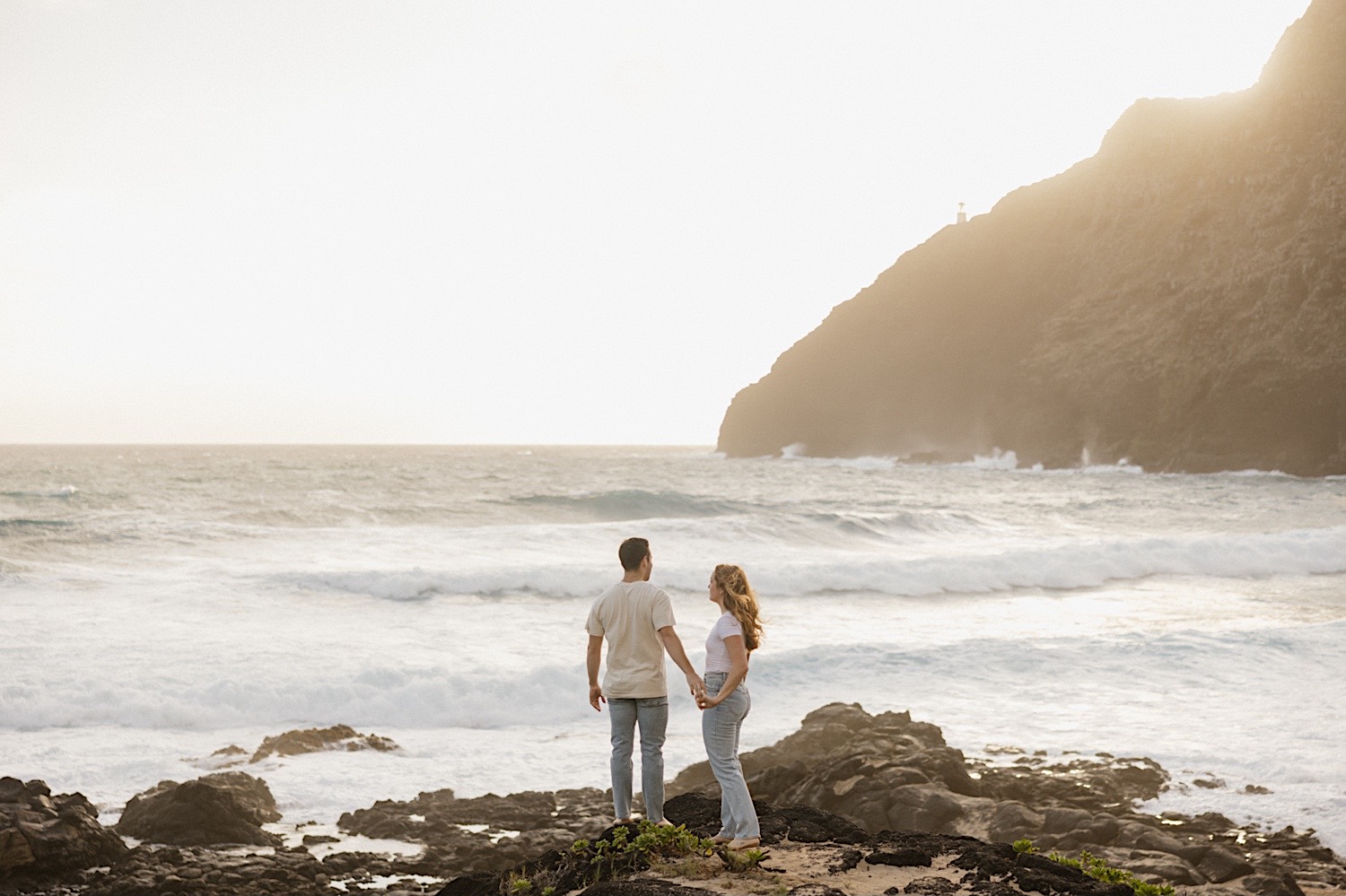 A couple hold hands while standing on the shore of Makapuu Beach during their romantic honeymoon session on Oahu, Hawaii