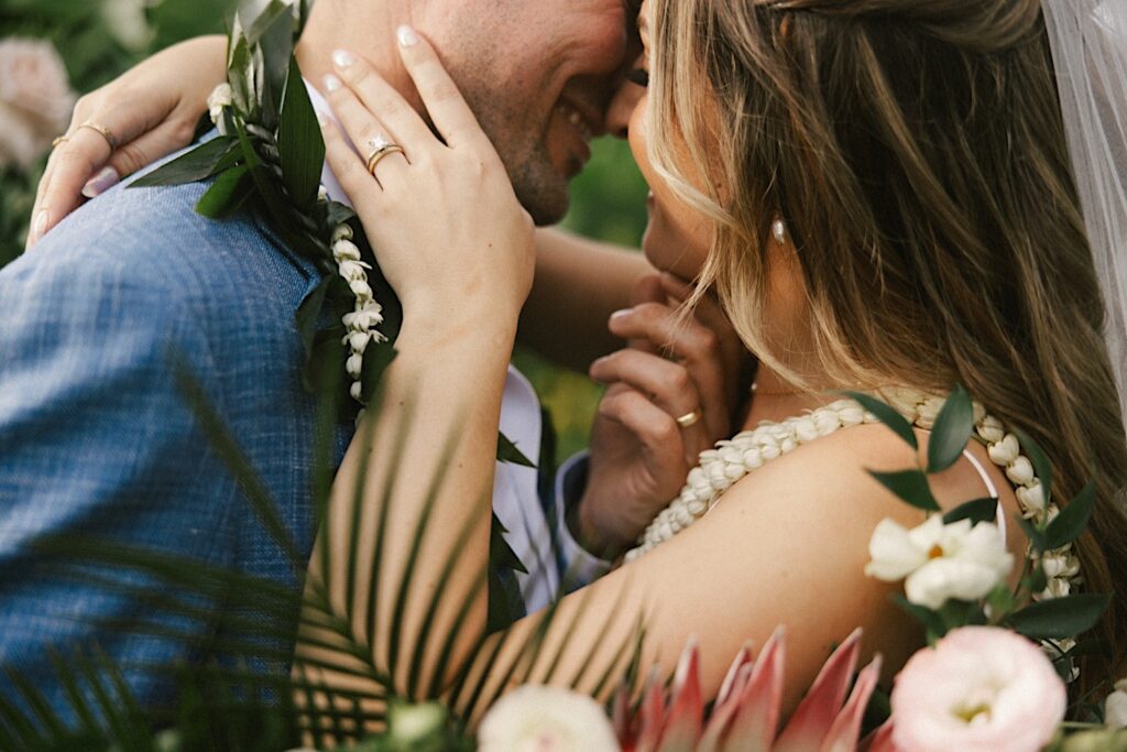Close up photo of a bride and groom smiling as they're about to kiss one another during their wedding at their venue, Male'ana Gardens on Oahu