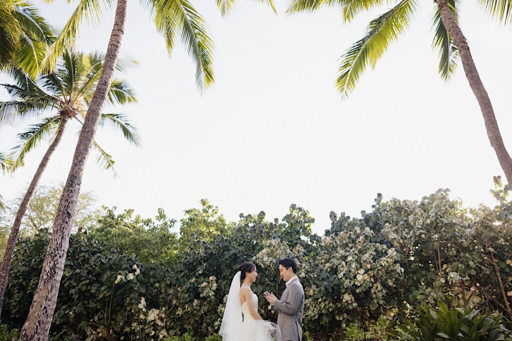 On the grounds of the Four Seasons Oahu in Ko Olina, a bride listens as the groom reads his private vows to her before their elopement ceremony