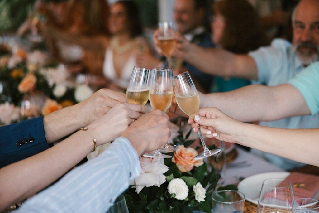 Guests of an intimate wedding at the venue, Male'ana Gardens on Oahu raise their glasses together for a toast