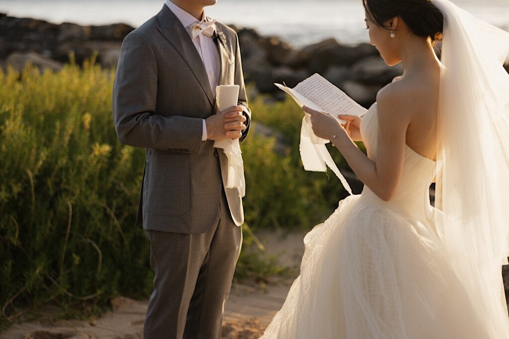 Close up photo of a bride reading her vows to the groom while they stand on a beach together during their elopement at the Four Seasons Oahu in Ko Olina