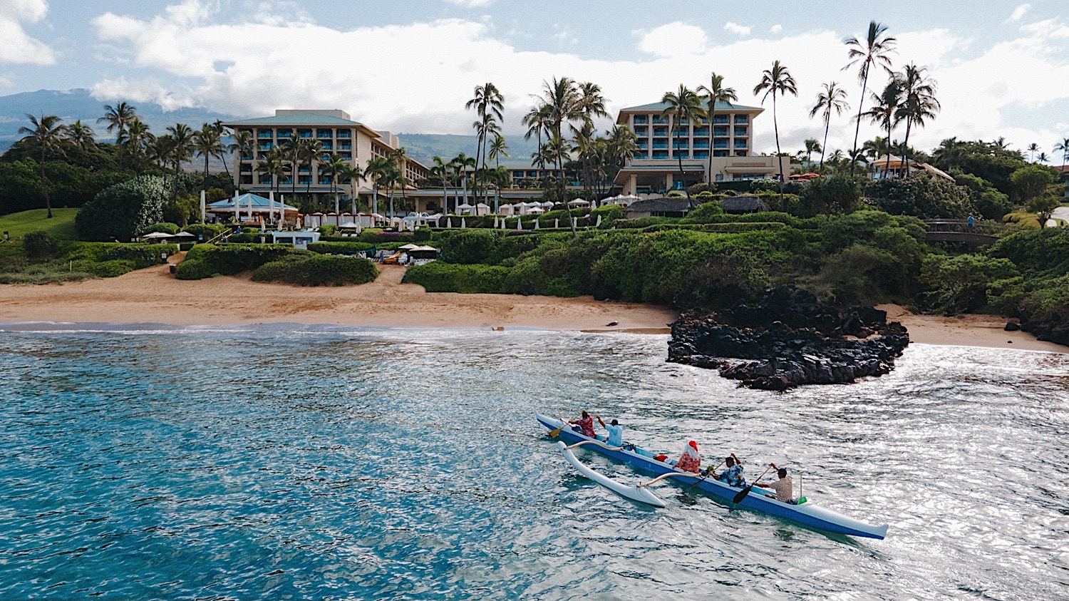 Kayakers row towards land and the Four Seasons Resort Maui at Wailea