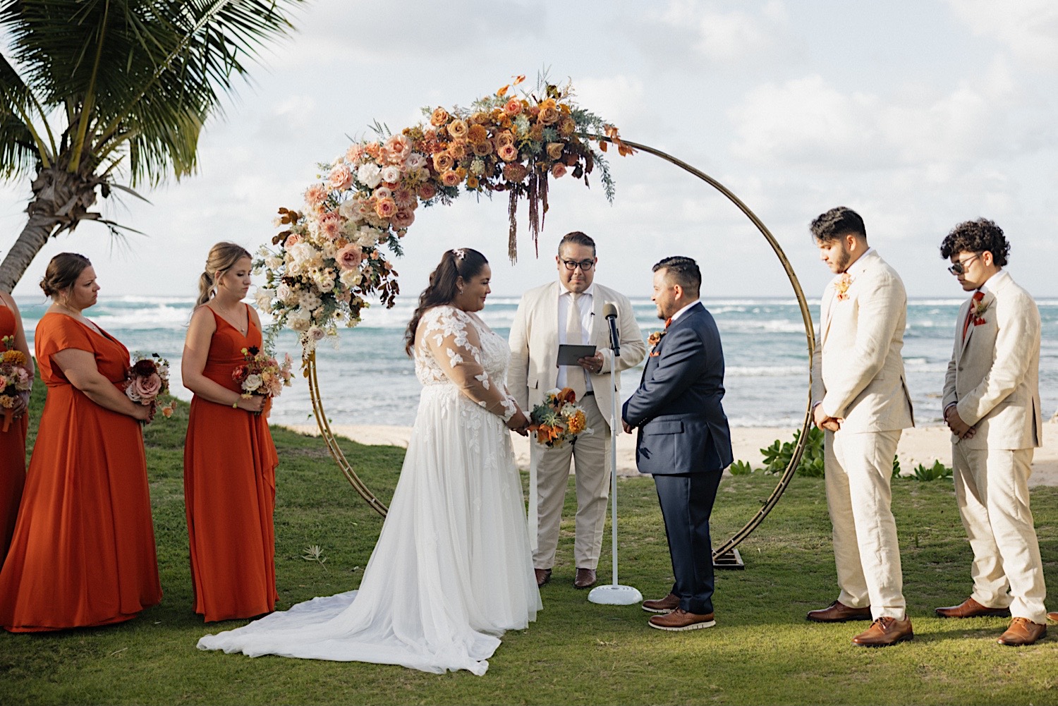 A wedding ceremony takes place in front of the ocean at a villa on Oahu
